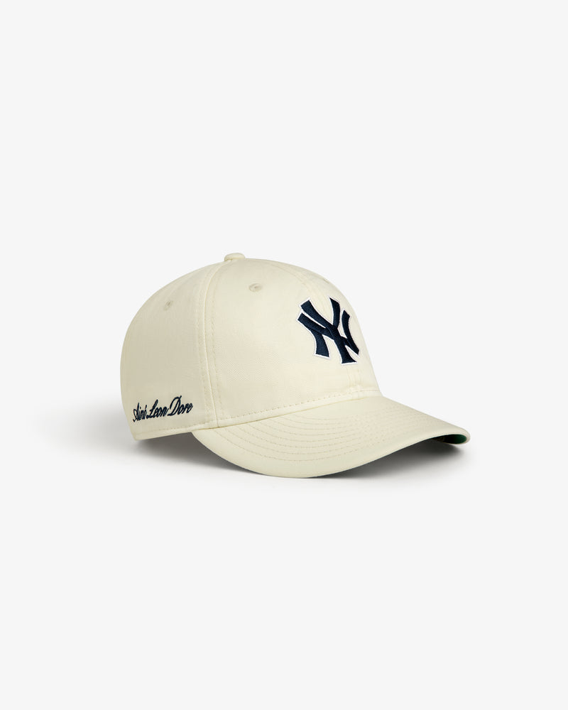 ALD / New Era Yankees Retro Fit Hat in cream with a navy NY logo and script text, shown on a white background.