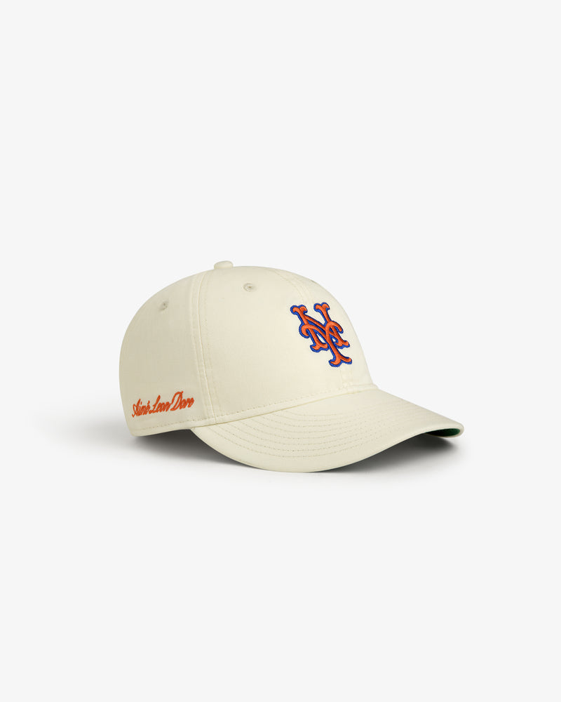 ALD / New Era Mets Retro Fit Hat: cream cap with blue and orange NY logo, red side script, on white background.