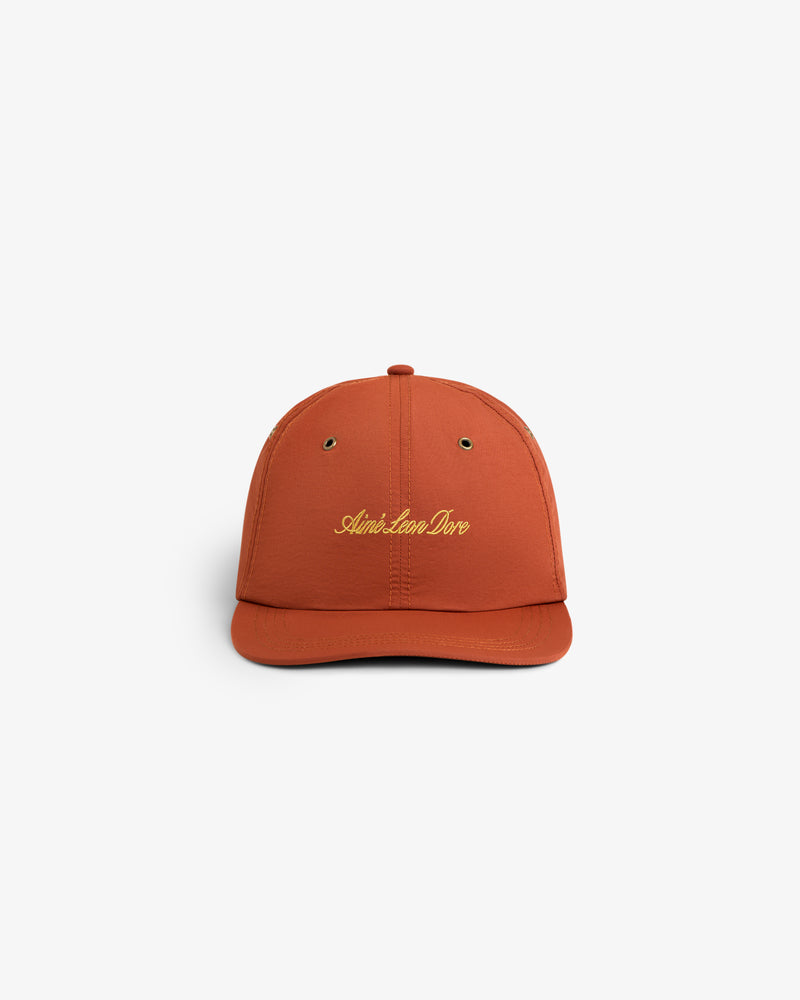 Rust-colored Script Sport Hat with gold Aimé Leon Dore embroidery, shown on a white background.