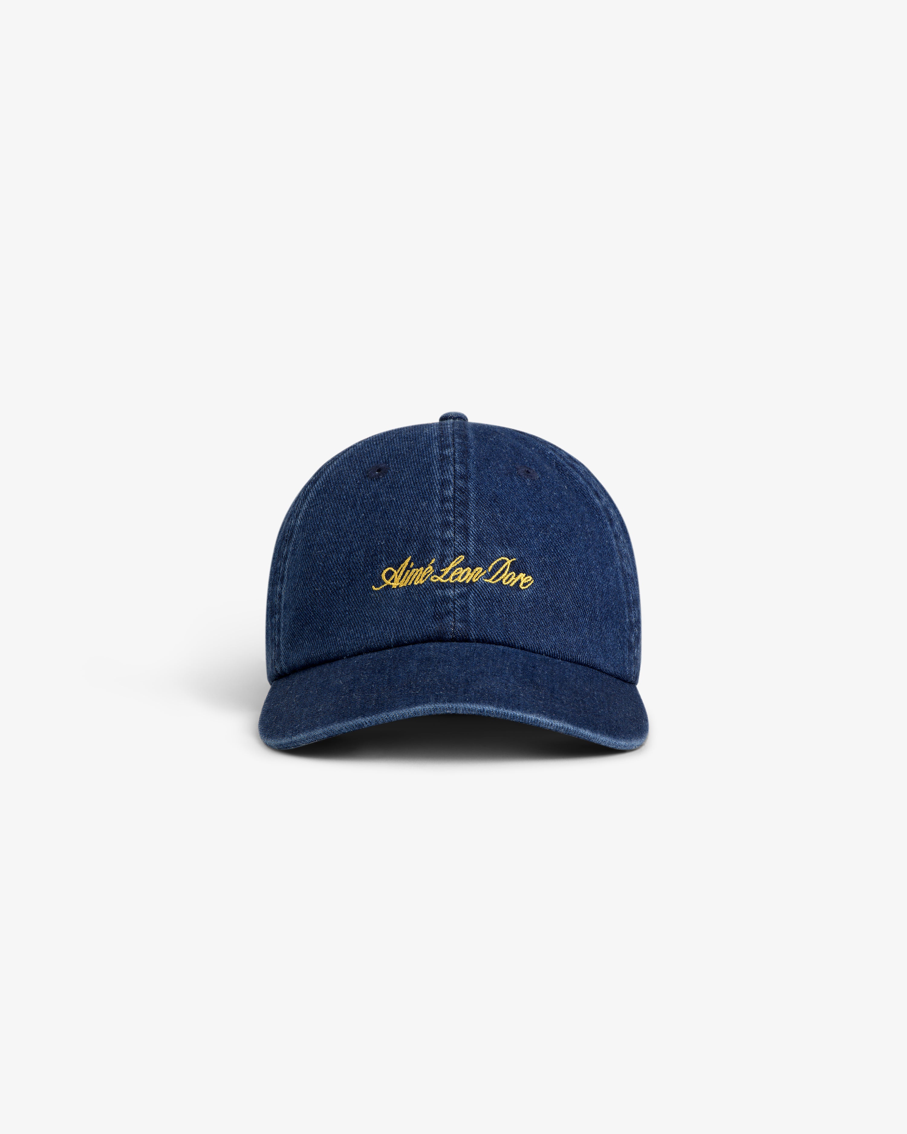 The Denim Script Hat is a dark blue denim baseball cap with yellow embroidered cursive text on the front.