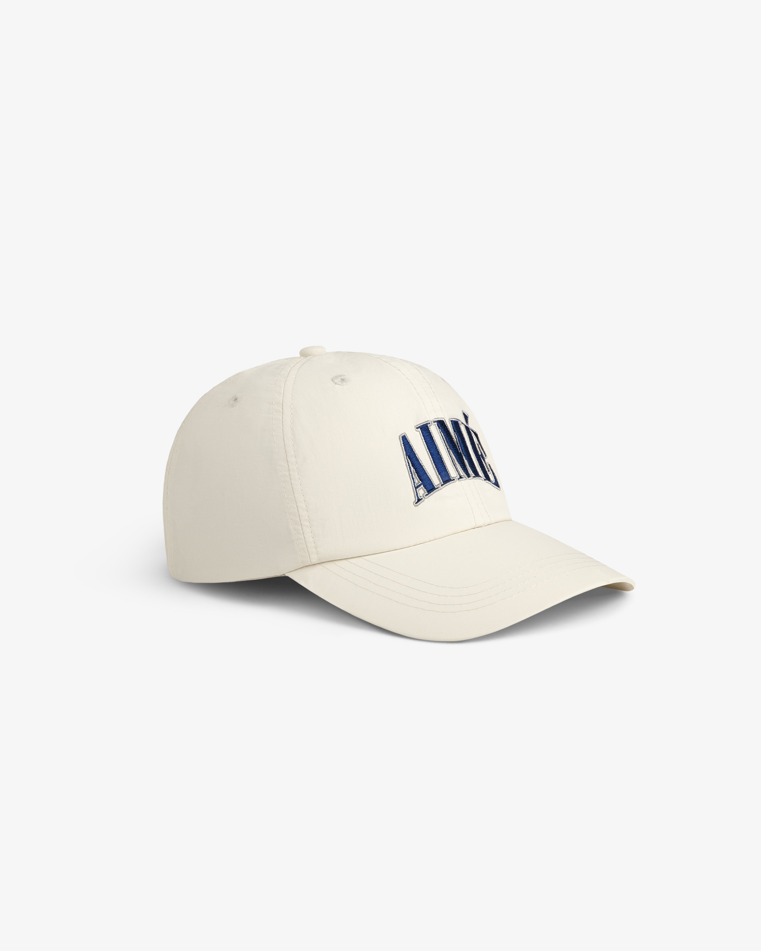 Cream-colored Nylon Crusher Hat with blue embroidered letters on the front, shown on a plain white background.