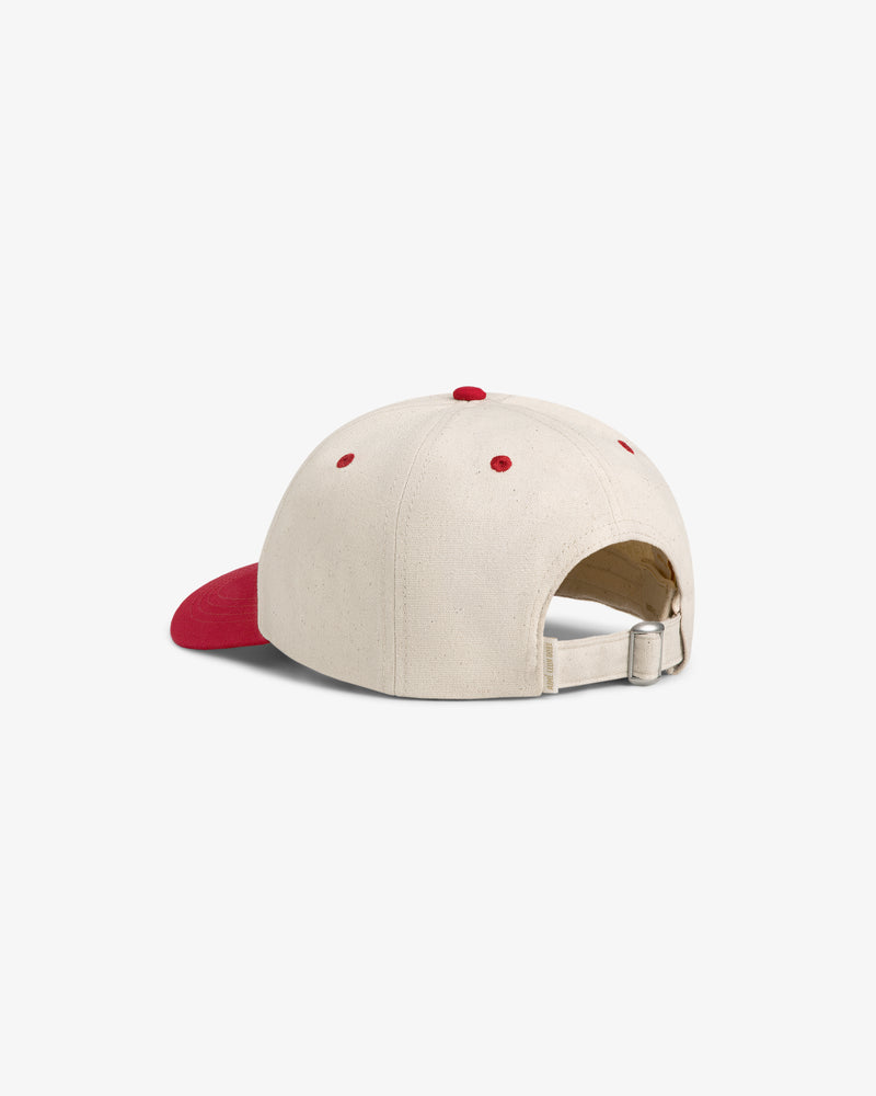 The Krylon Logo Hat is a beige baseball cap with a red brim, red accents, and an adjustable strap with metal clasp.