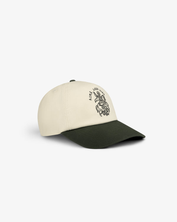 The Saint George Logo Hat features a cream crown, dark green brim, and a black graphic on the front.