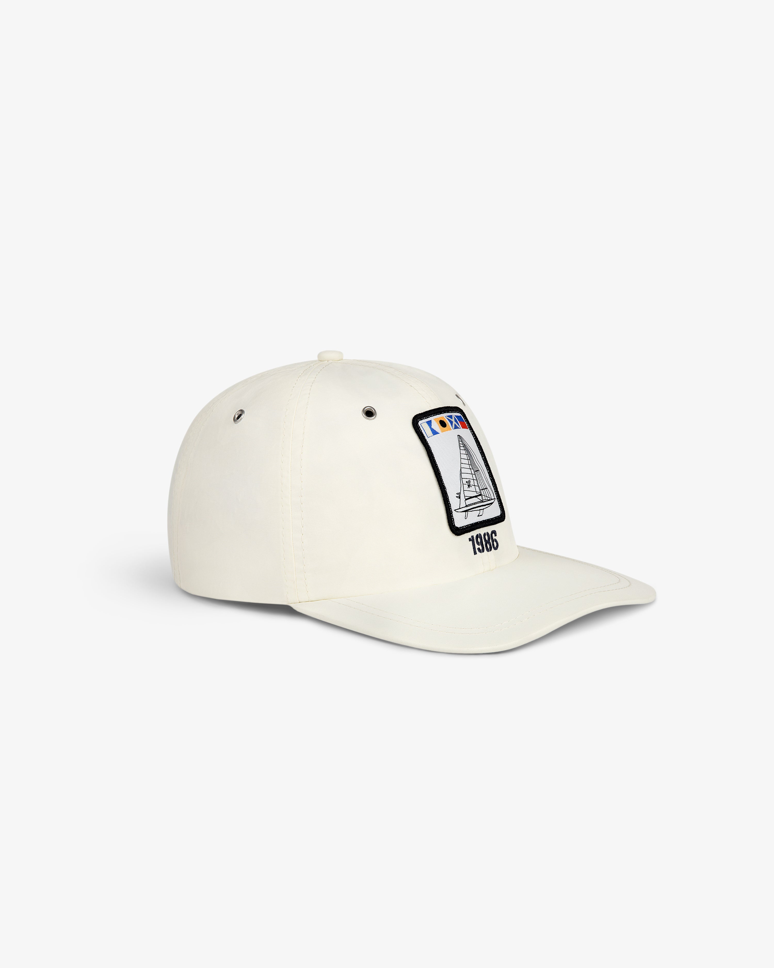 Nylon Deck Hat in off-white with a front patch of a sailboat, flags, and "1986" embroidery.