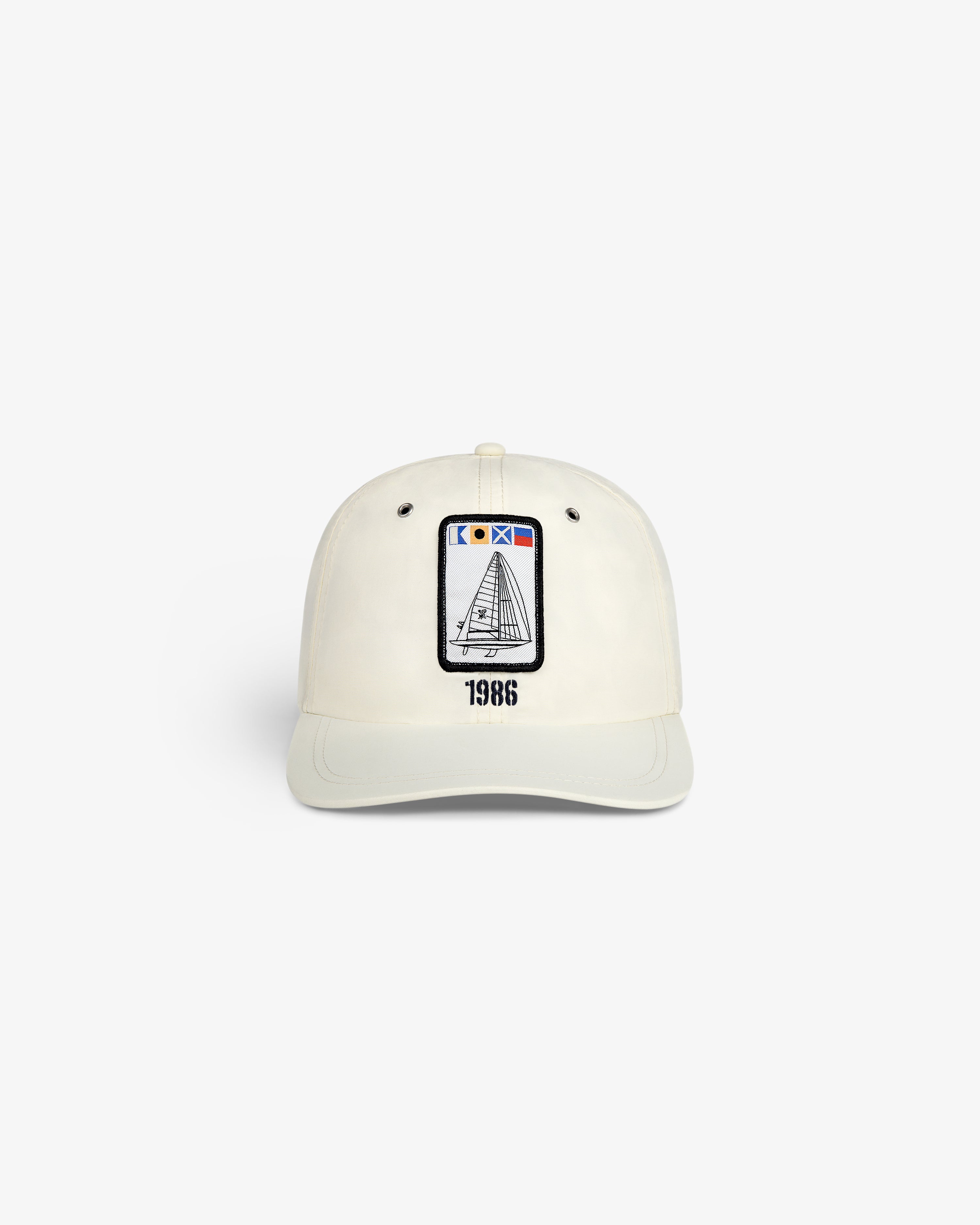 Front view of the Nylon Deck Hat in off-white with a sailboat patch and "1986" embroidered below.