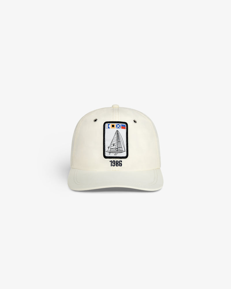 Front view of the Nylon Deck Hat in off-white with a sailboat patch and "1986" embroidered below.