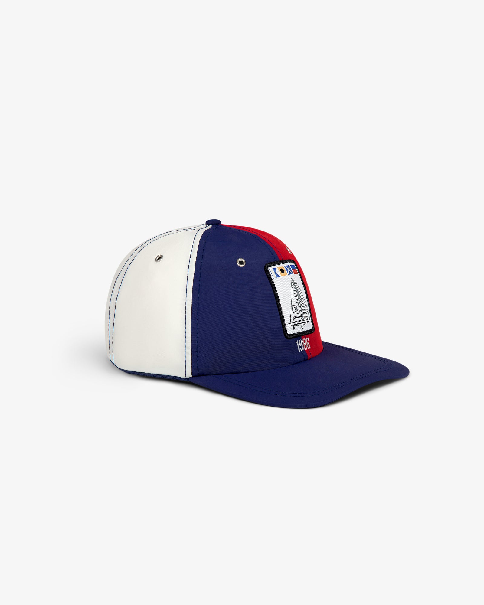 The Nylon Deck Hat is a blue, white, and red cap with a 1985 sailboat patch on the front.