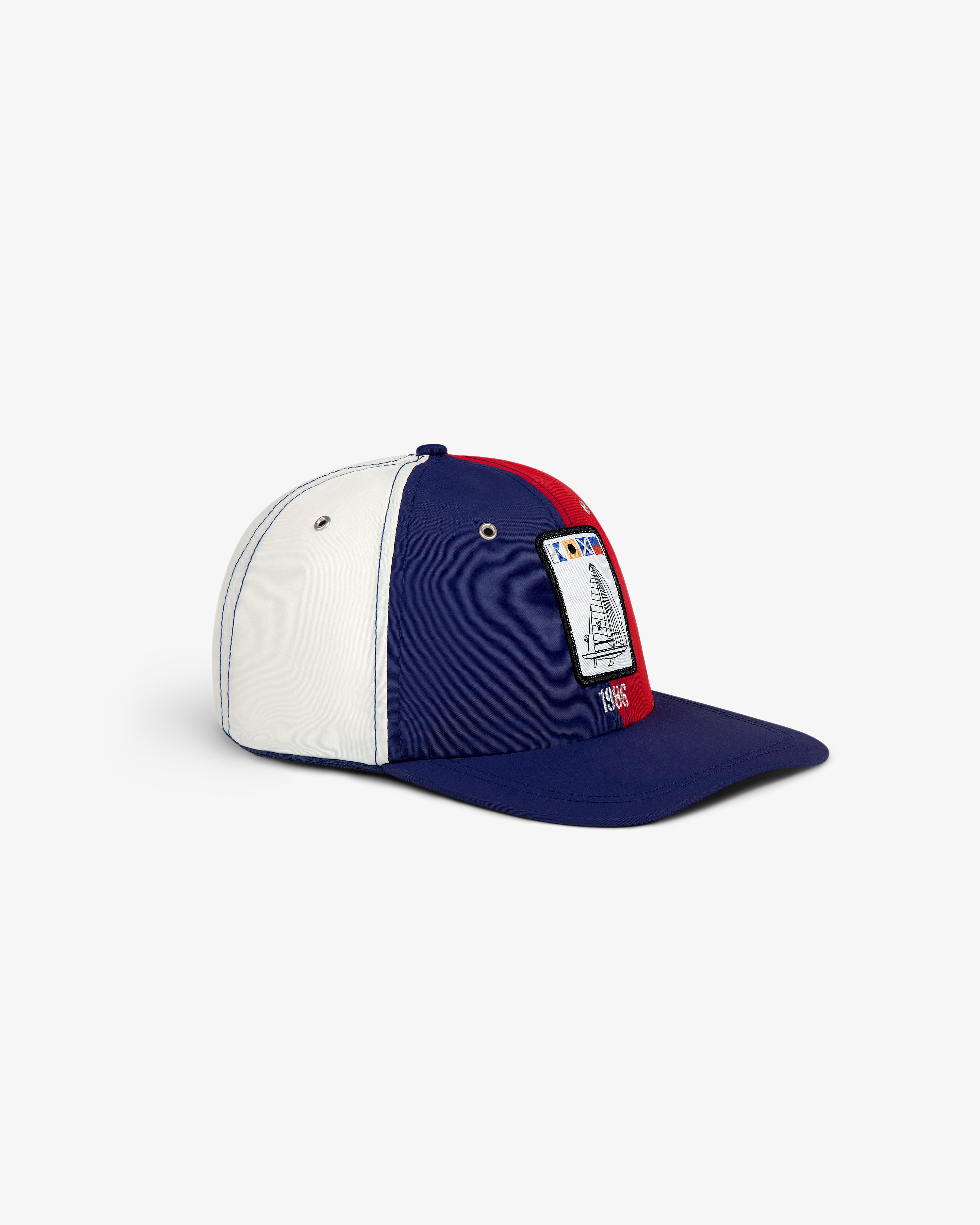 The Nylon Deck Hat is a blue, white, and red cap with a 1985 sailboat patch on the front.