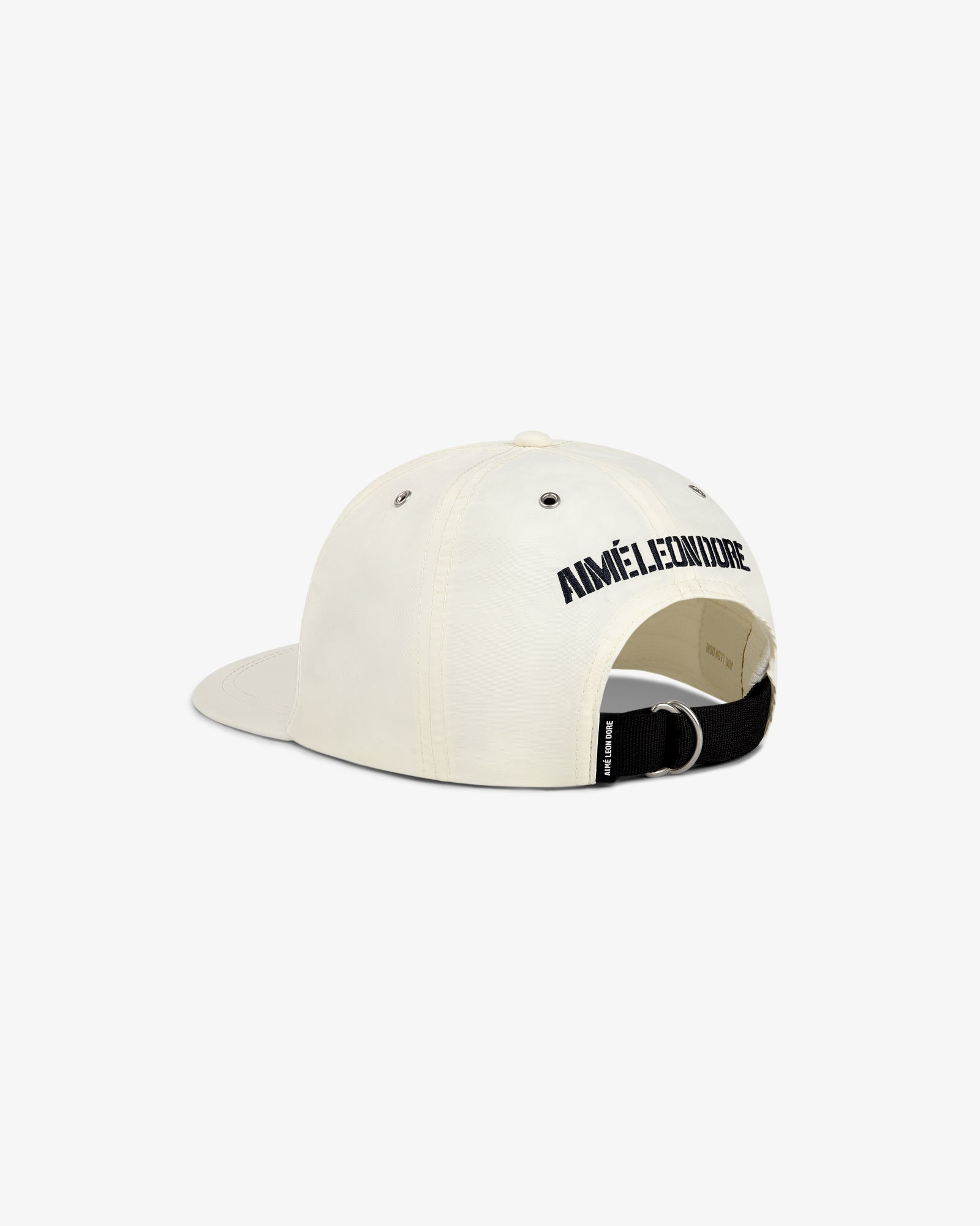 The Nylon Deck Hat is a cream baseball cap with AIMÉ LEON DORE in black text above the adjustable back strap.