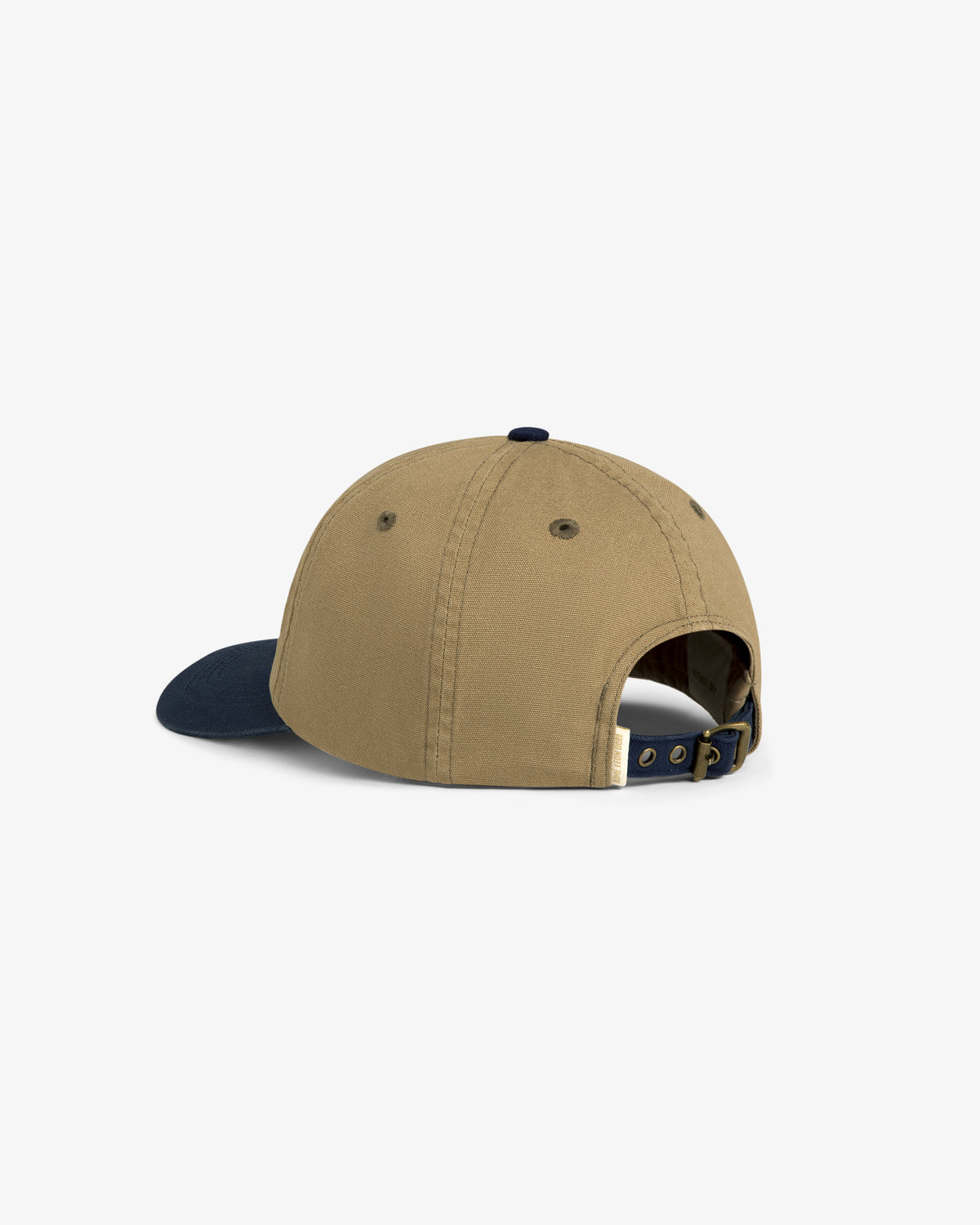 The Colorblock Lure Hat is a tan cap with a navy brim, shown from the back with an adjustable strap and buckle.