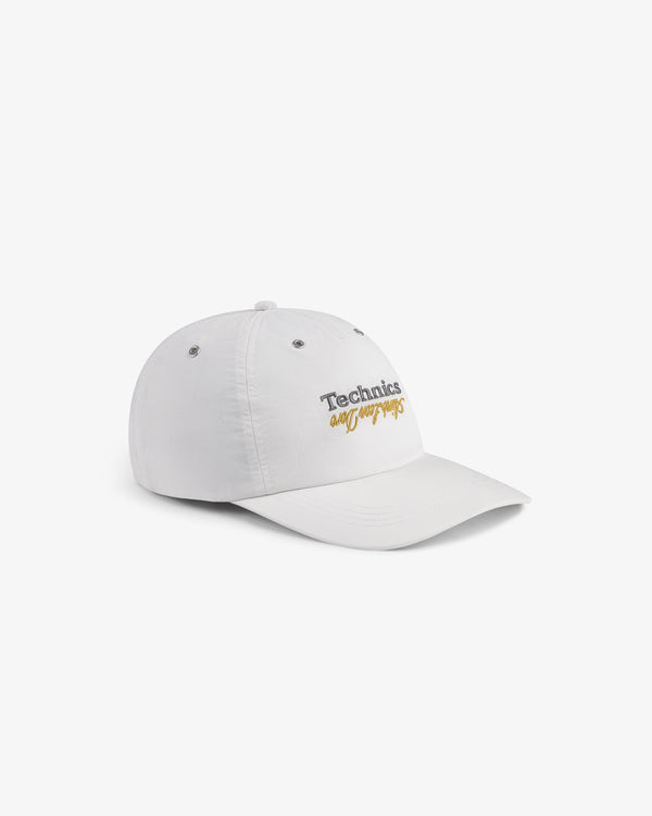 ALD / Technics Nylon Logo Hat in white with gold cursive logo embroidery, shown on a white background.
