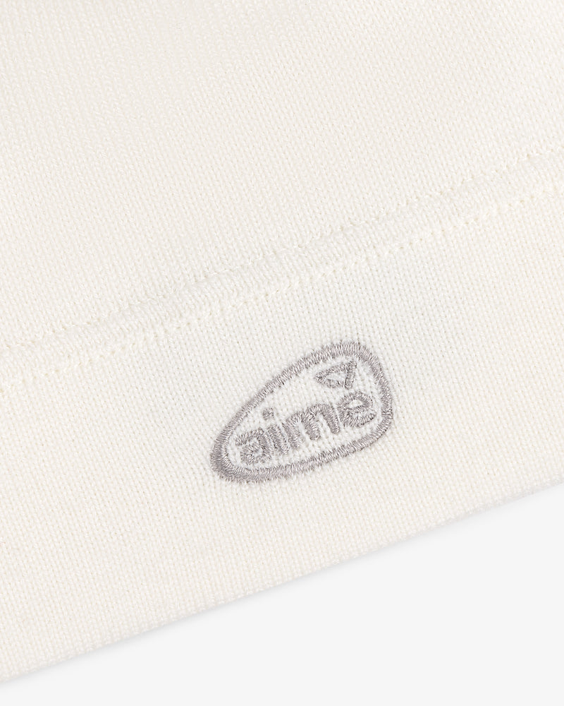 Close-up of a white ALD Golf Skull Cap with a small, gray embroidered oval logo that reads AIME.