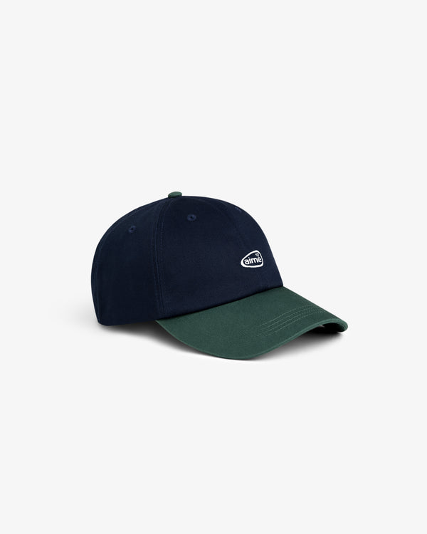 The ALD Golf Logo Hat is navy blue with a dark green brim and features a small white embroidered logo on the front.
