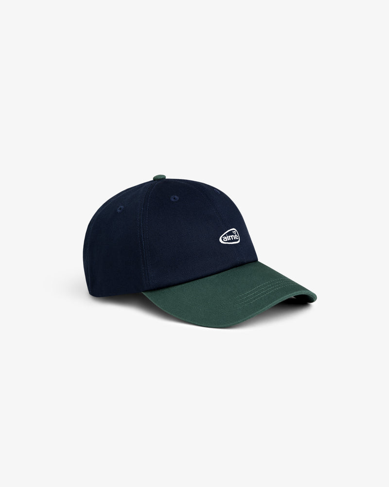 The ALD Golf Logo Hat is navy blue with a dark green brim and features a small white embroidered logo on the front.