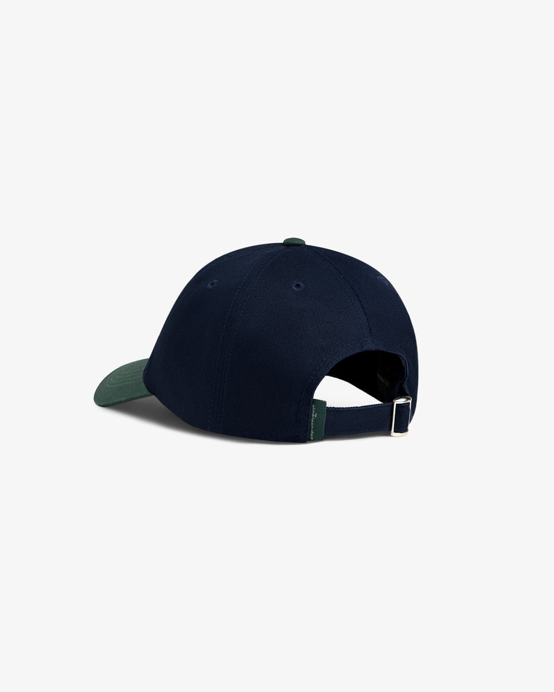 The ALD Golf Logo Hat in navy with a green brim features an adjustable strap and metal clasp, shown from the back.