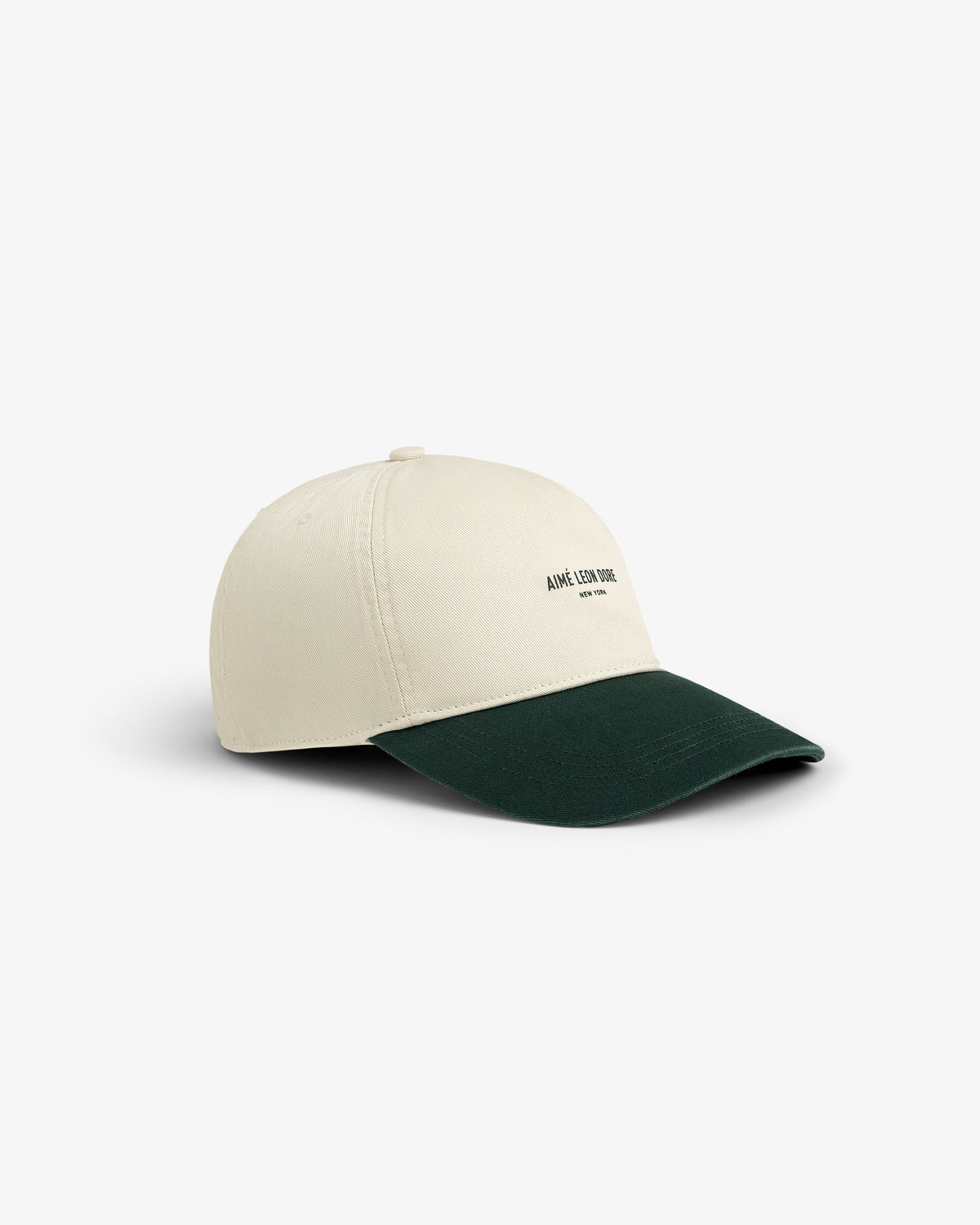 Micro Logo Hat: beige cap with dark green brim, small black text logo on front, shown on white background.
