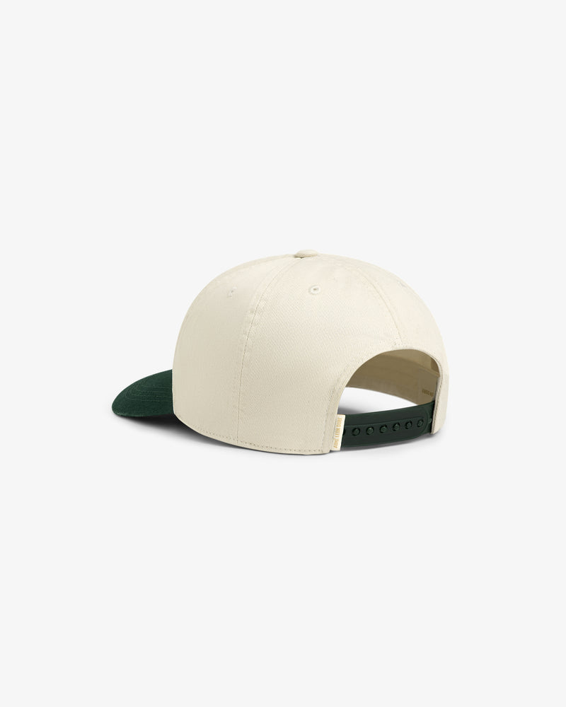 The Micro Logo Hat is cream-colored with a dark green brim and an adjustable strap, shown from the back.
