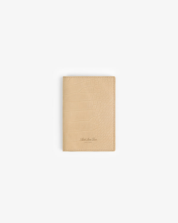 Croc-Embossed Nubuck Passport Holder in beige shown on a plain white background with subtle embossed texture.