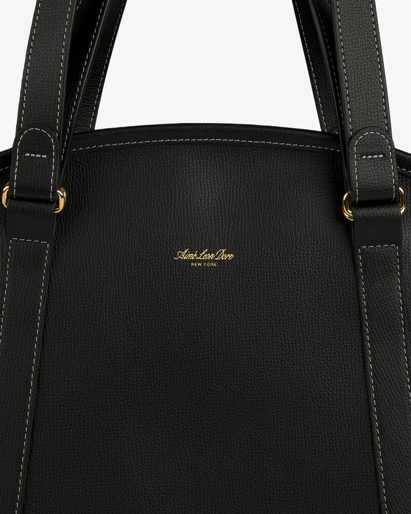 Close-up of a Full Grain Leather Weekender Bag in black with gold hardware, white stitching, and "Adelaide Doro" logo.