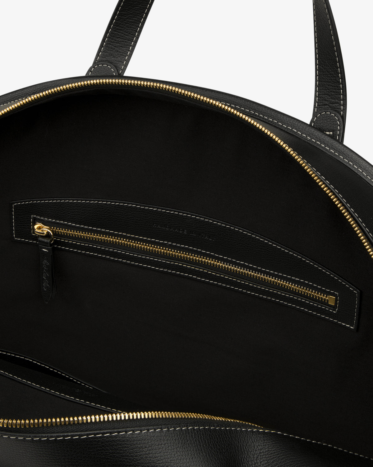 Close-up of the Full Grain Leather Weekender Bag interior, with a gold zipper pocket and black fabric lining.