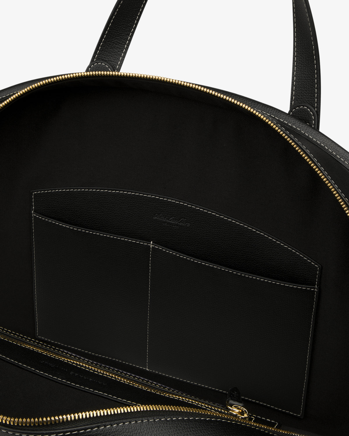 Close-up of the Full Grain Leather Weekender Bag interior with gold zipper, inner pockets, and dark fabric lining.
