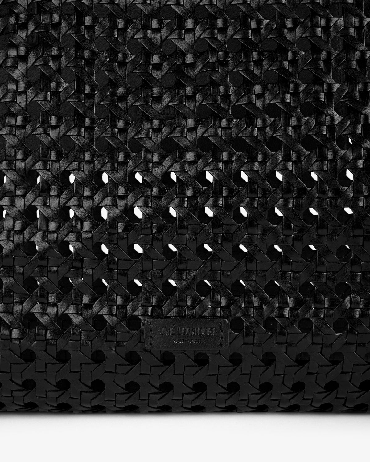 Close-up of the Woven Leather Tote Bag in black, featuring a small embossed label near the bottom.