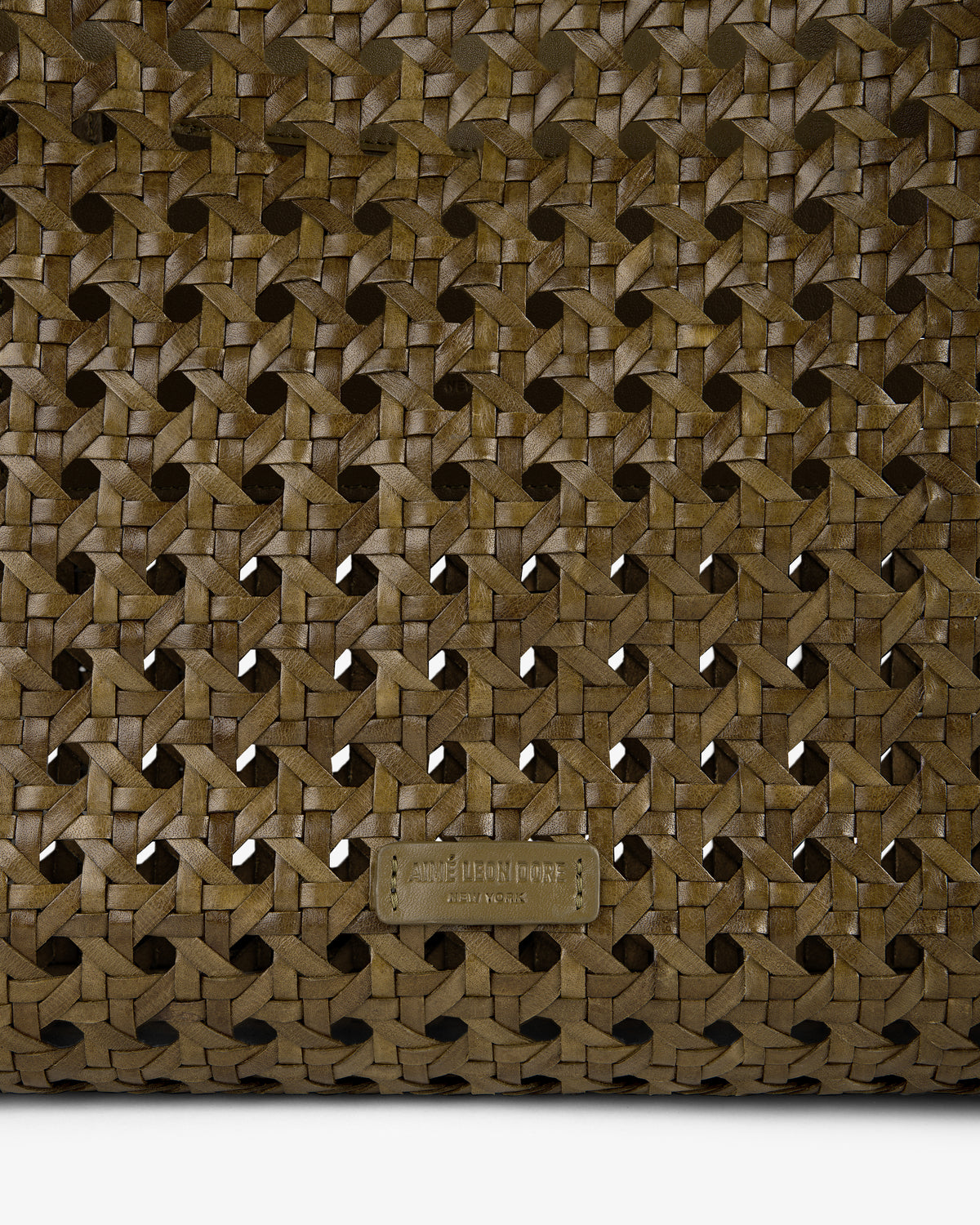 Close-up of the Woven Leather Tote Bag in brown, featuring a small embossed AMI PARIS label at the bottom.