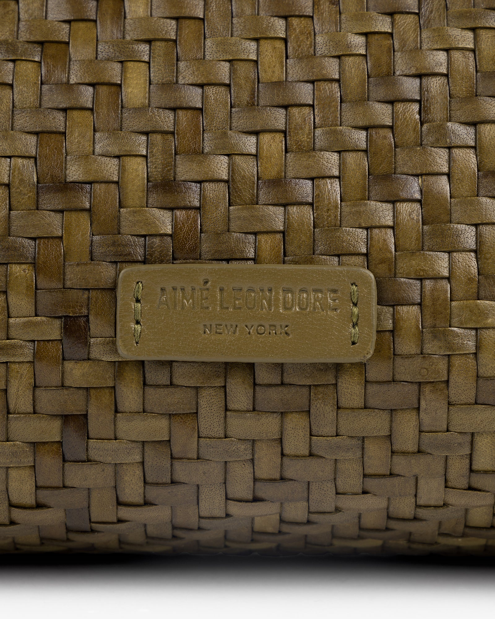 Close-up of the Woven Leather Shoulder Bag with an AIMÉ LEON DORE NEW YORK label stitched on the front.