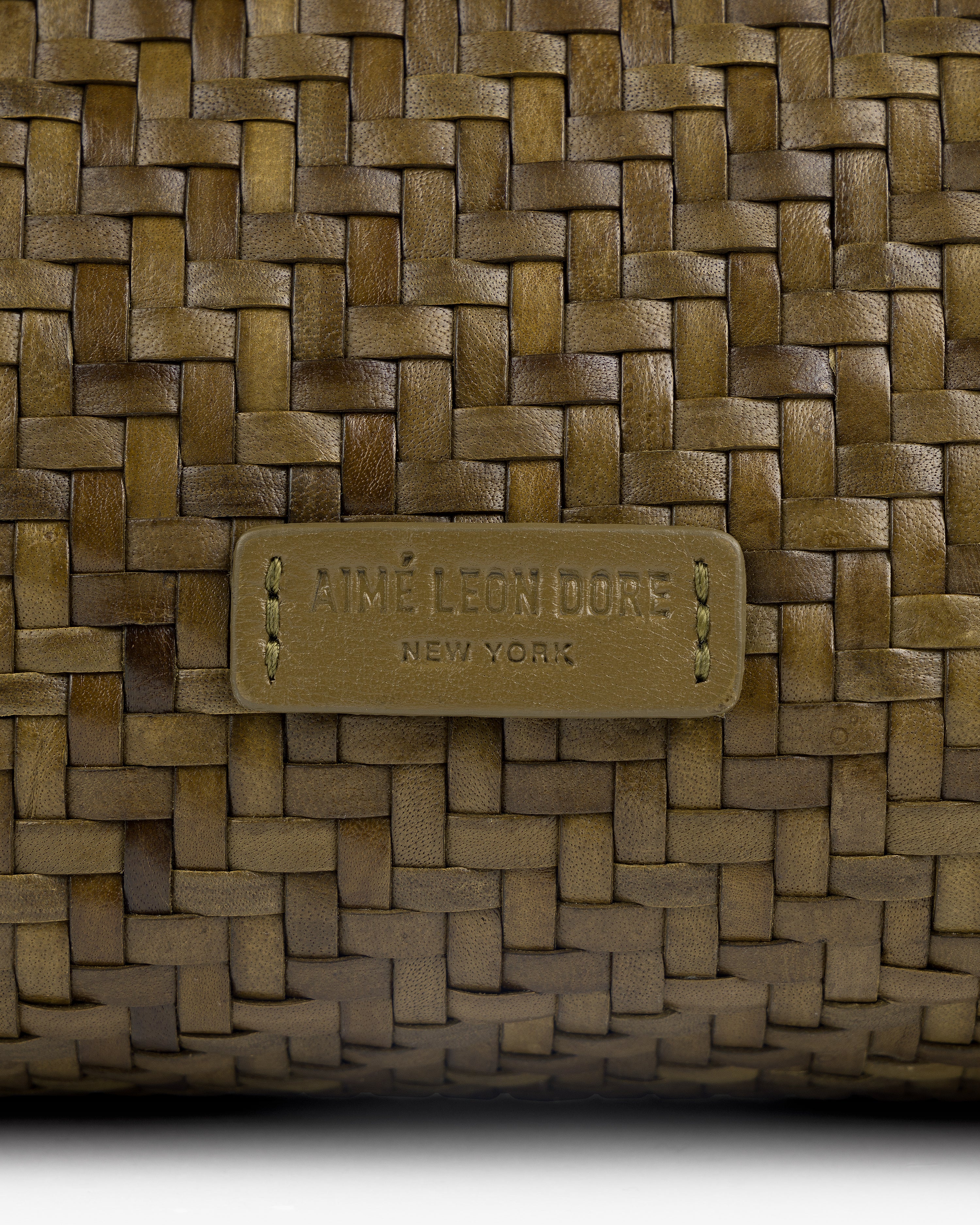 Close-up of the Woven Leather Shoulder Bag with an AIMÉ LEON DORE NEW YORK label stitched on the front.