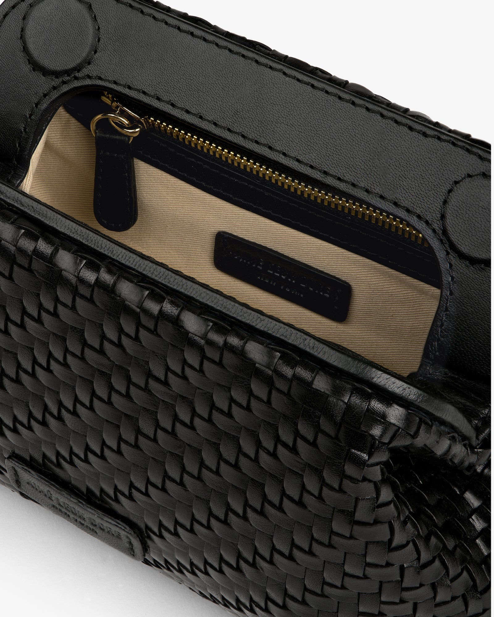 Close-up of the Woven Leather Shoulder Bag, open to reveal a beige interior, zip pocket, and black label.