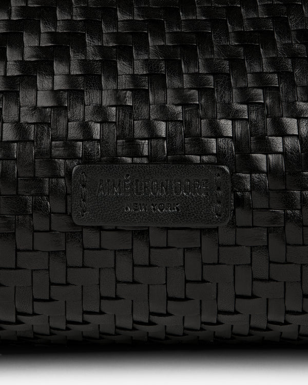 Close-up of a black Woven Leather Shoulder Bag with an embossed Aimé Leon Dore New York label.