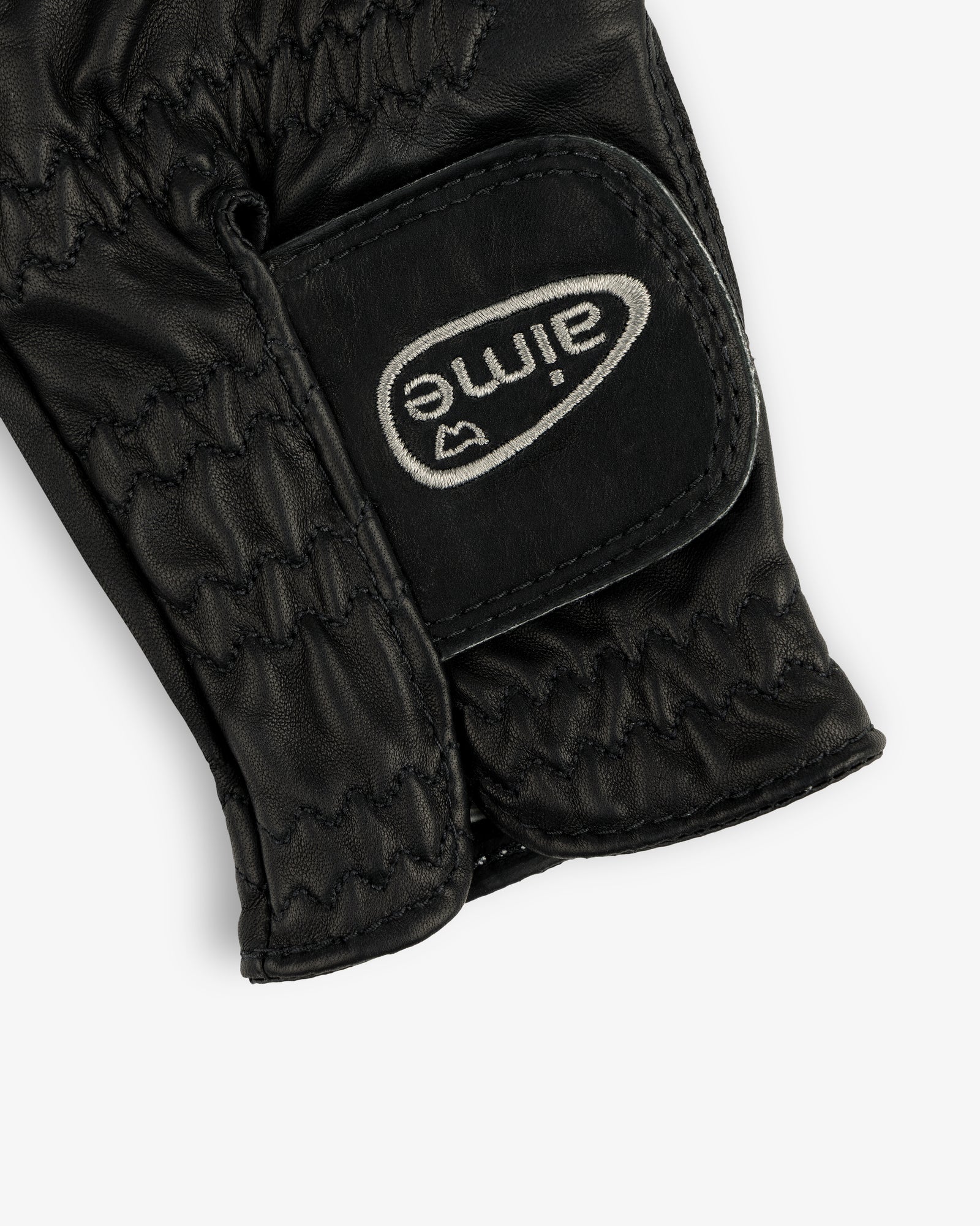 Close-up of the ALD / FootJoy StaSof Heritage Glove (Left), black leather with stitching and a white aimé Velcro strap.