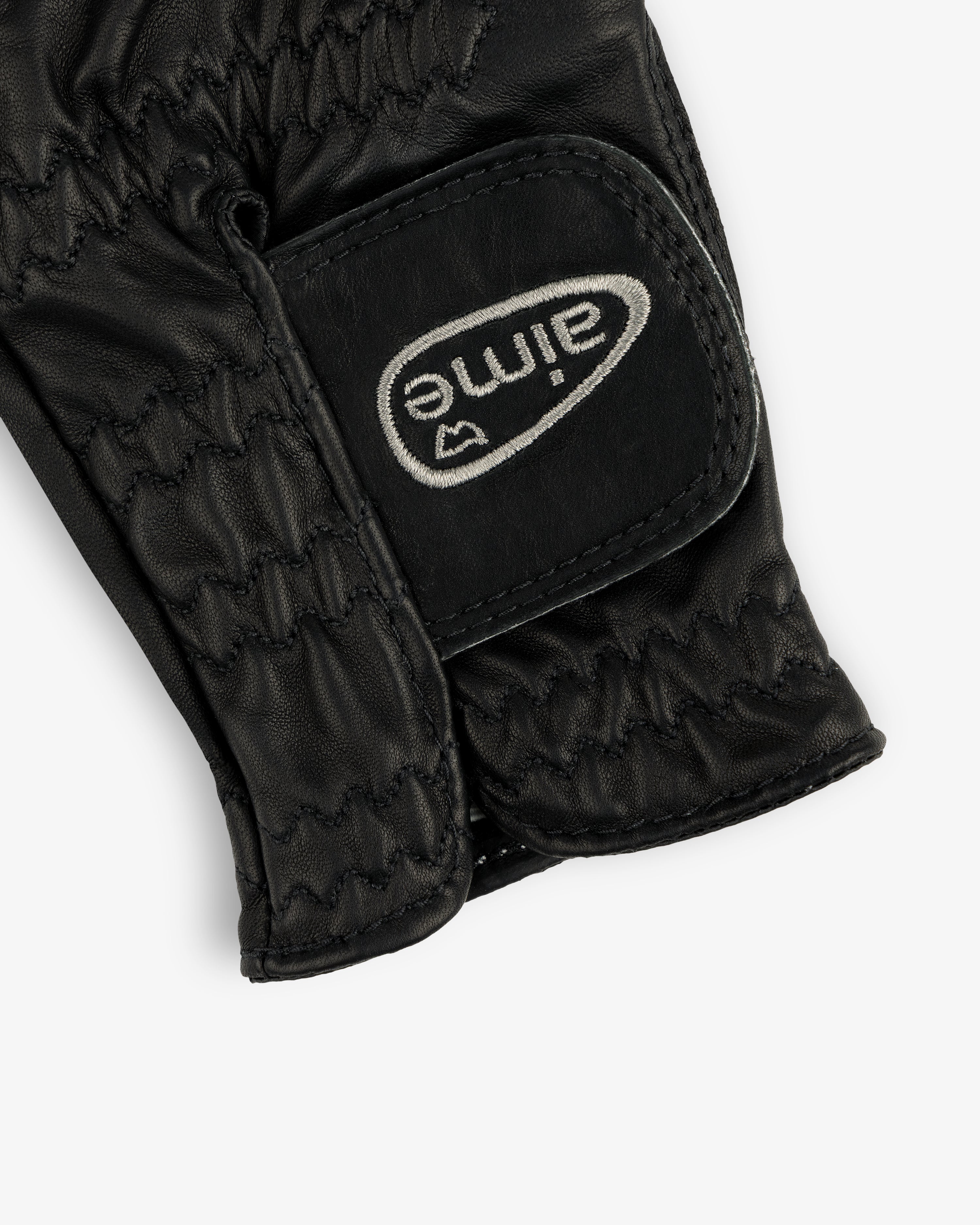 Close-up of the ALD / FootJoy StaSof Heritage Glove (Left), black leather with stitching and a white aimé Velcro strap.