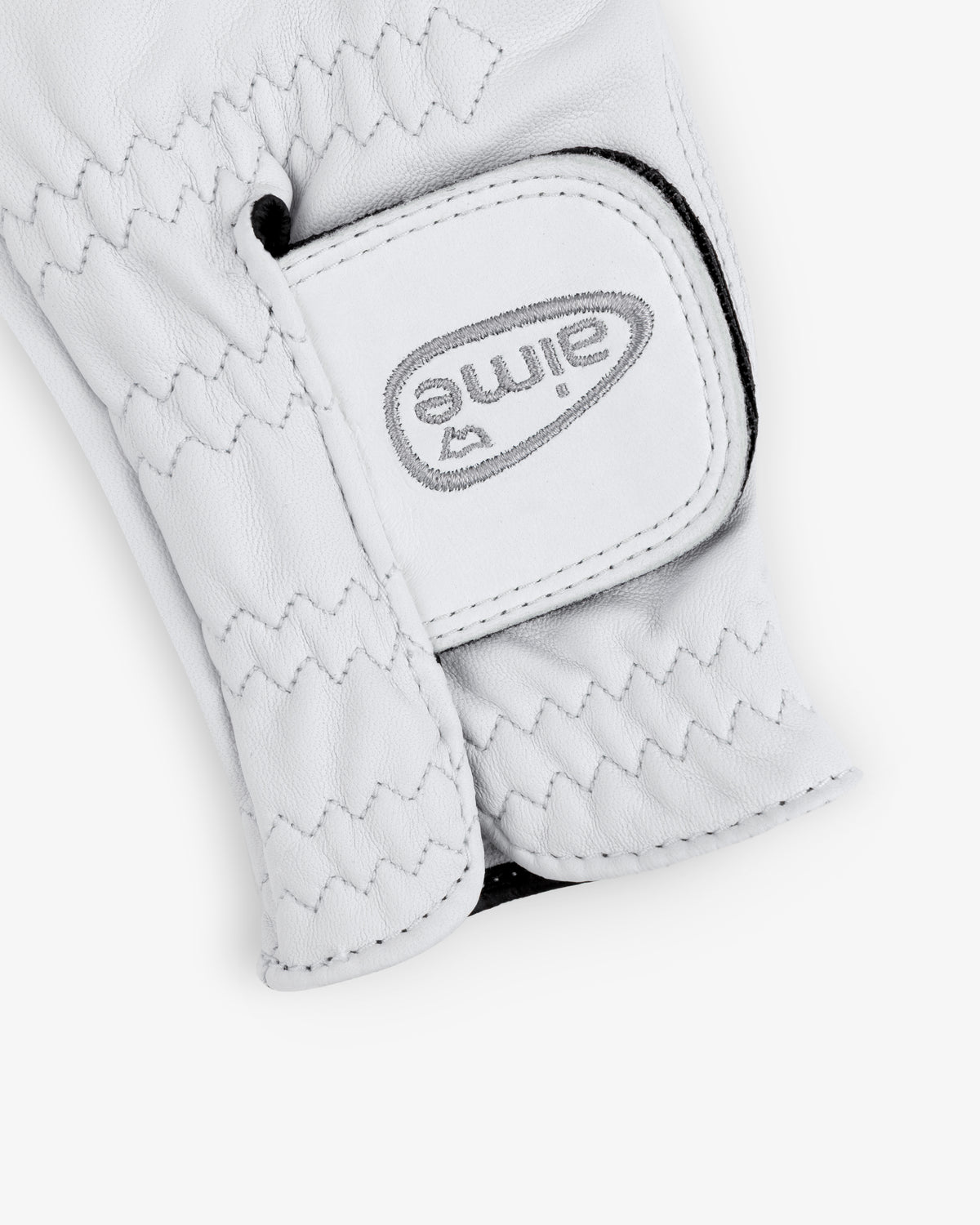 Close-up of ALD / FootJoy StaSof Heritage Glove (Left) in white leather with zigzag stitching and gray Aime text on Velcro.