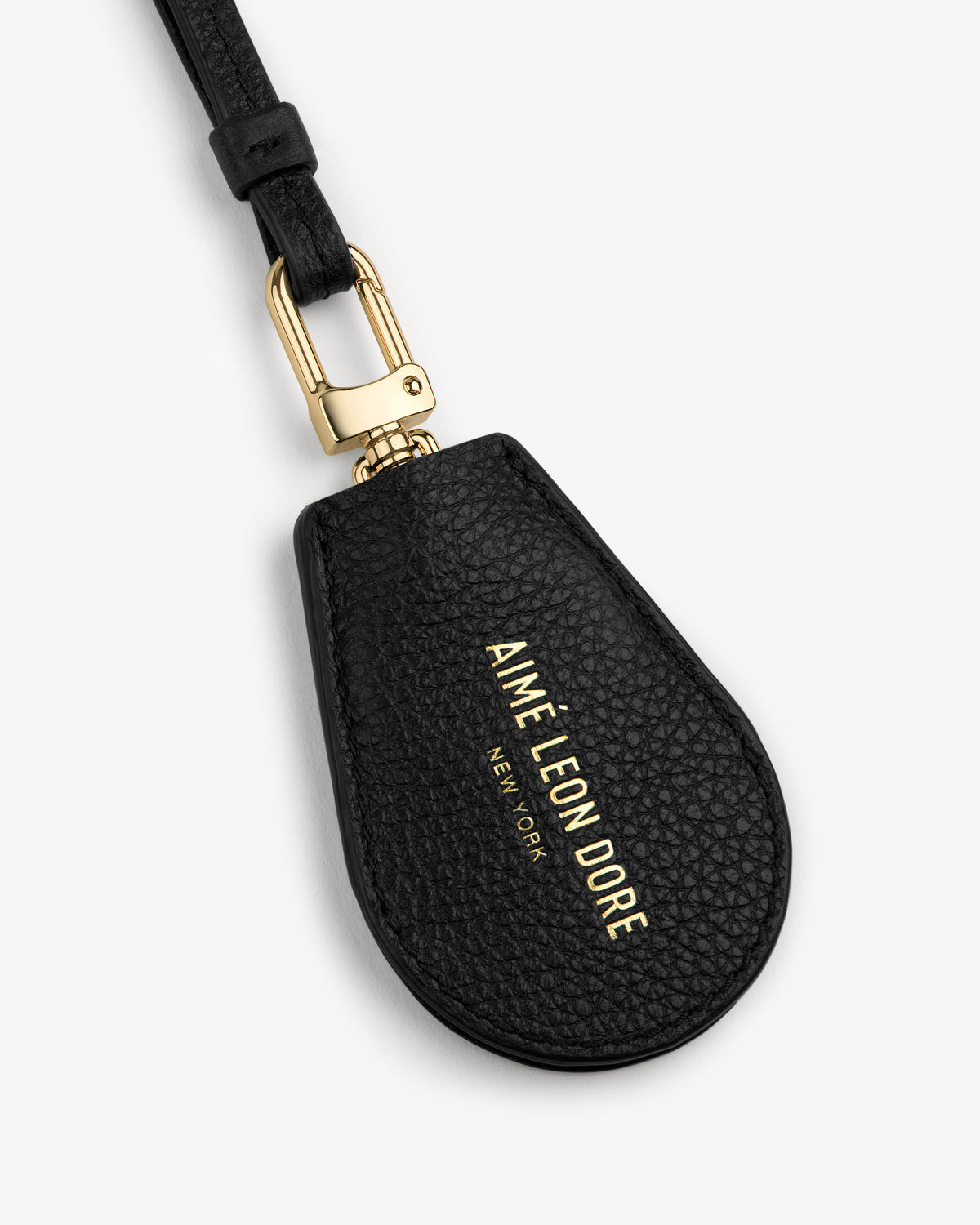 Black leather key cover with gold hardware and AIMÉ LEON DORE NEW YORK text embossed in gold.