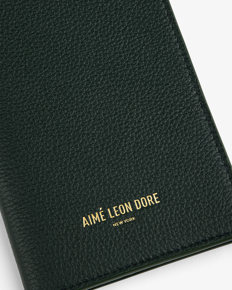 Close-up of a textured dark green Leather Passport Holder with AIMÉ LEON DORE NEW YORK embossed in gold.