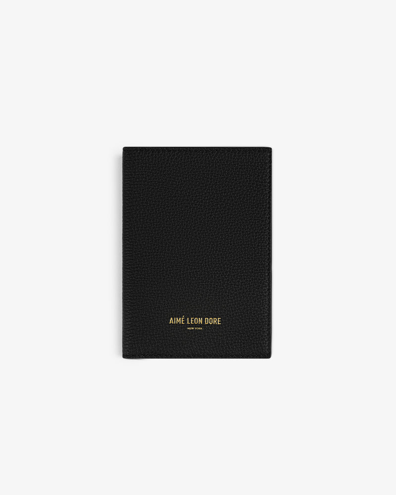 Black textured Leather Passport Holder with AIMÉ LEON DORE gold lettering at the bottom center.