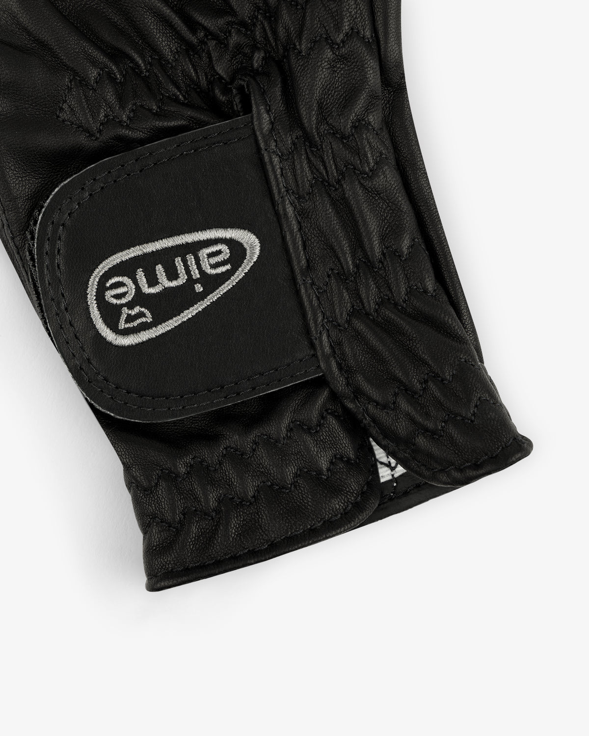 Close-up of ALD / FootJoy StaSof Heritage Glove (Right) in black leather with gray stitched logo and zigzag detail.
