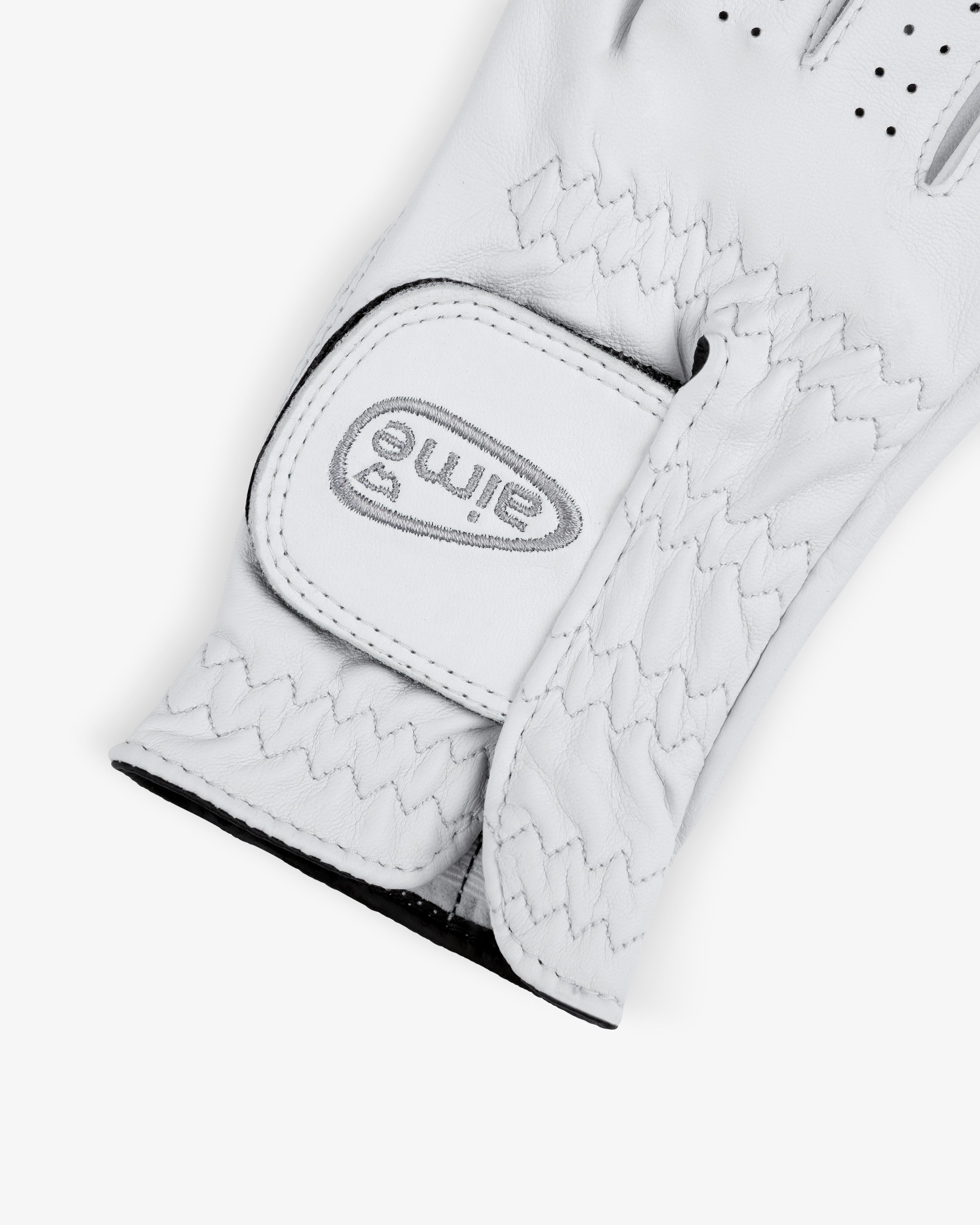 A close-up of the ALD / FootJoy StaSof Heritage Glove (Right) with a stitched strap and gray eimie logo on the fastener.