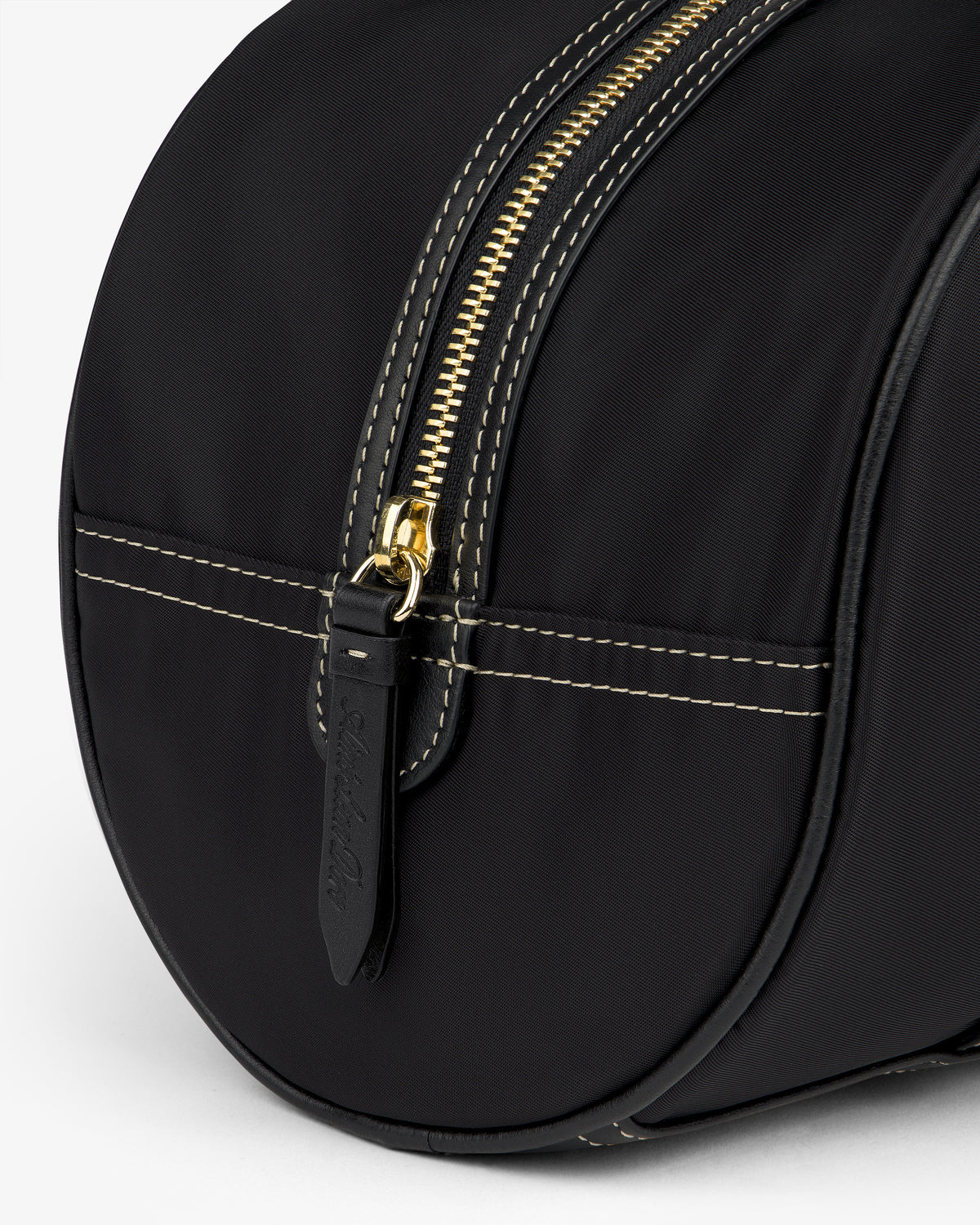 Close-up of the Mini Duffle Shoulder Bag in black with white stitching, gold zipper, and black leather pull.