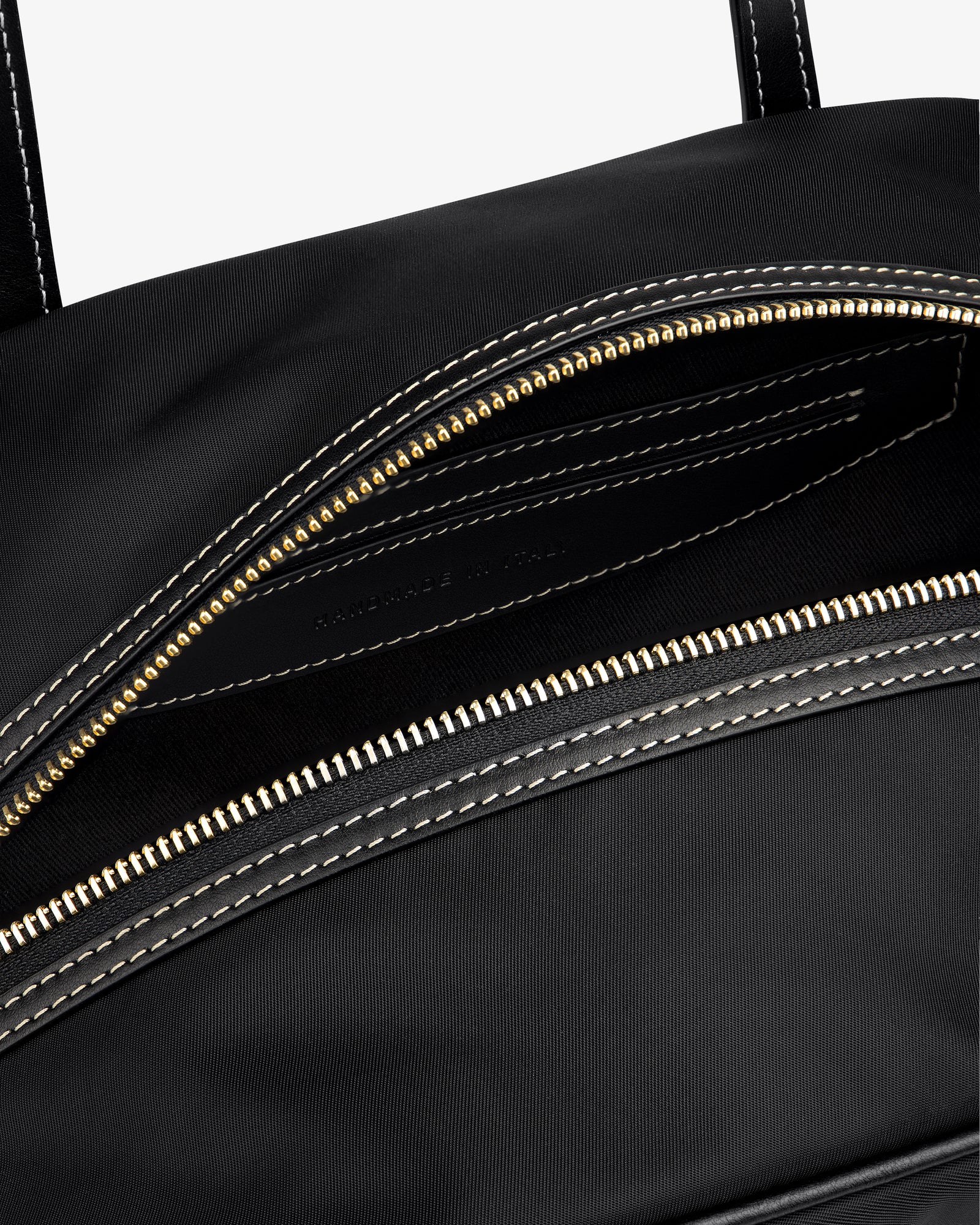 Close-up of the Mini Duffle Shoulder Bag in black with a gold zipper and white stitching around the opening.