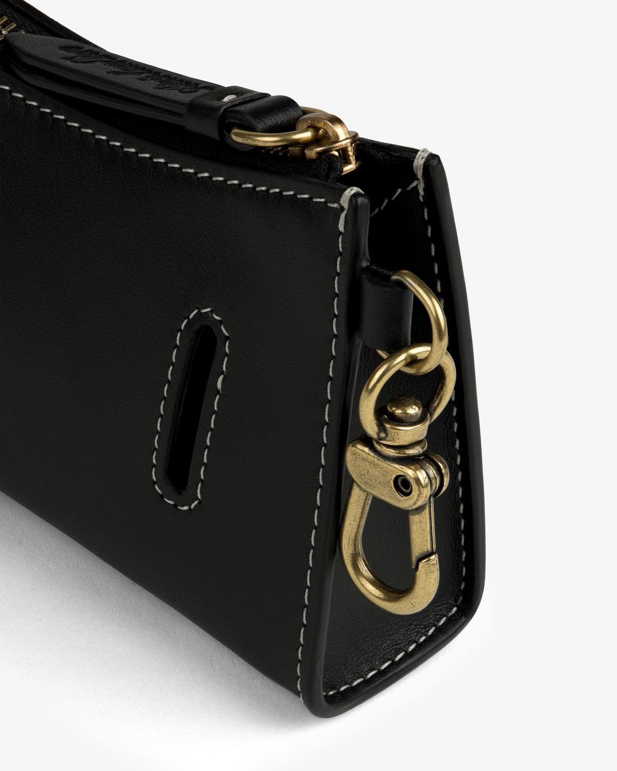 Close-up of Convertible Leather Belt Bag’s black leather corner with white stitching and gold clasp.