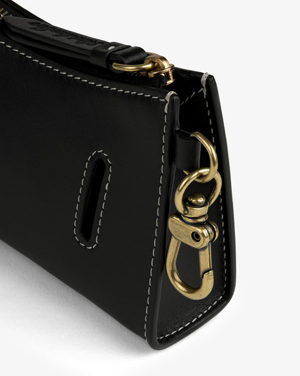 Close-up of Convertible Leather Belt Bag’s black leather corner with white stitching and gold clasp.