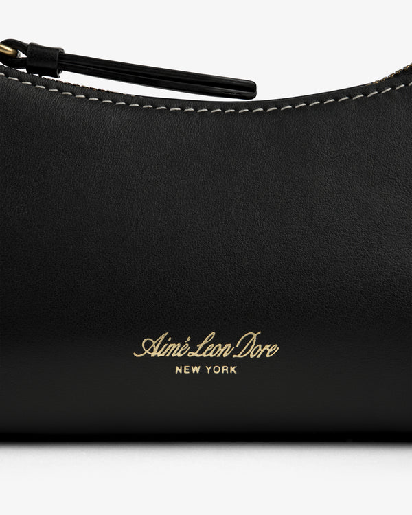 Close-up of the Convertible Leather Belt Bag with gold Aimé Leon Dore NEW YORK embossing and visible white stitching.