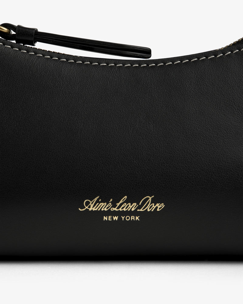 Close-up of the Convertible Leather Belt Bag with gold Aimé Leon Dore NEW YORK embossing and visible white stitching.
