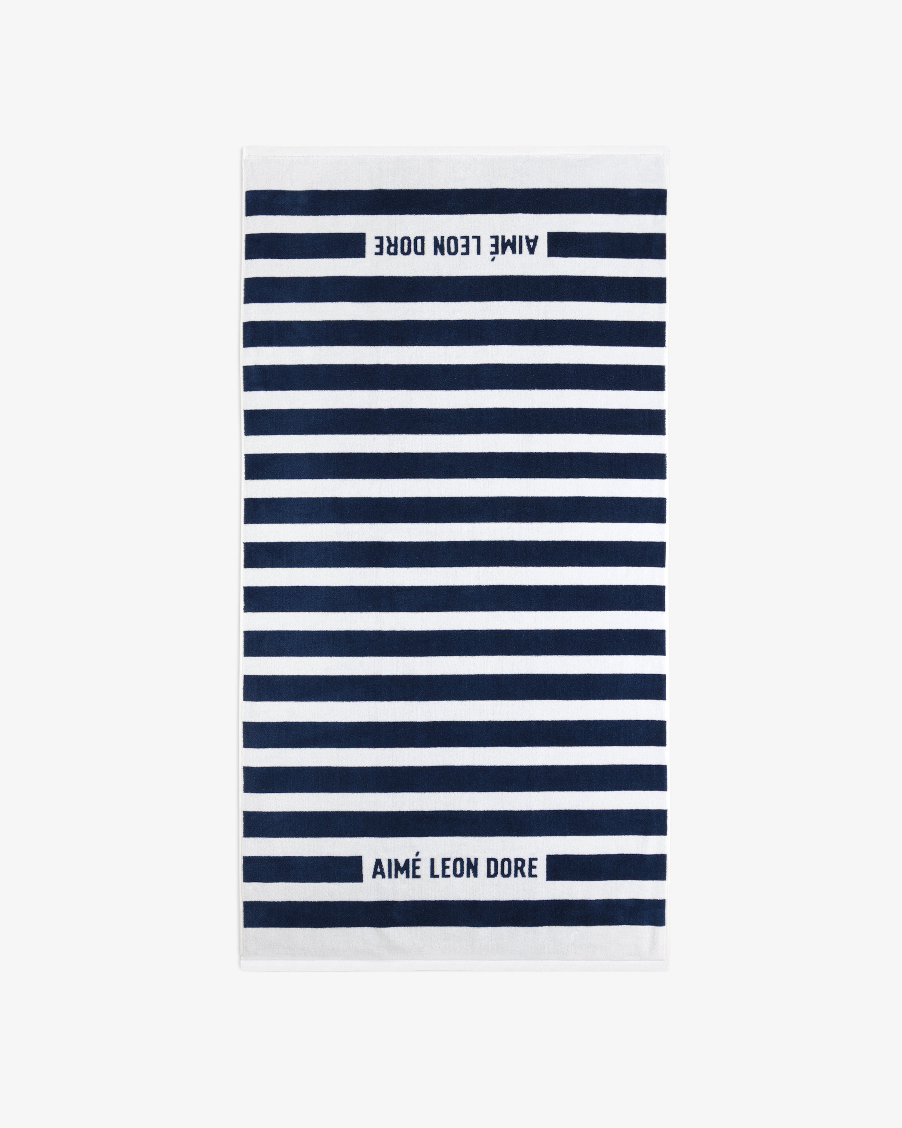 The Striped Beach Towel is white with navy blue horizontal stripes and AIMÉ LEON DORE text on both ends.