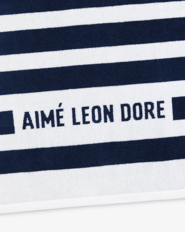 Striped Beach Towel in navy and white with bold navy AIMÉ LEON DORE text across one of the white stripes.