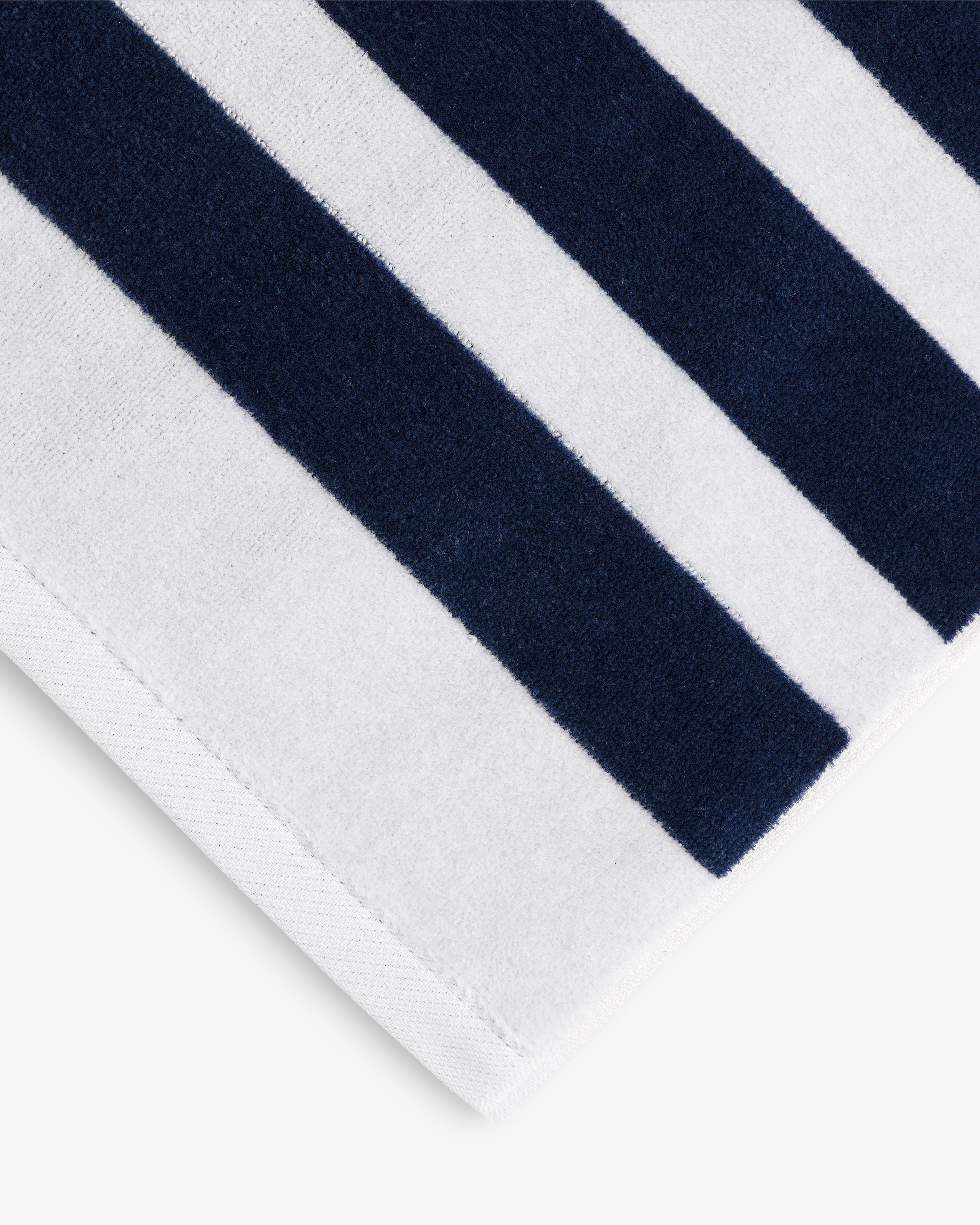 A close-up of the Striped Beach Towel featuring alternating navy blue and white vertical stripes.