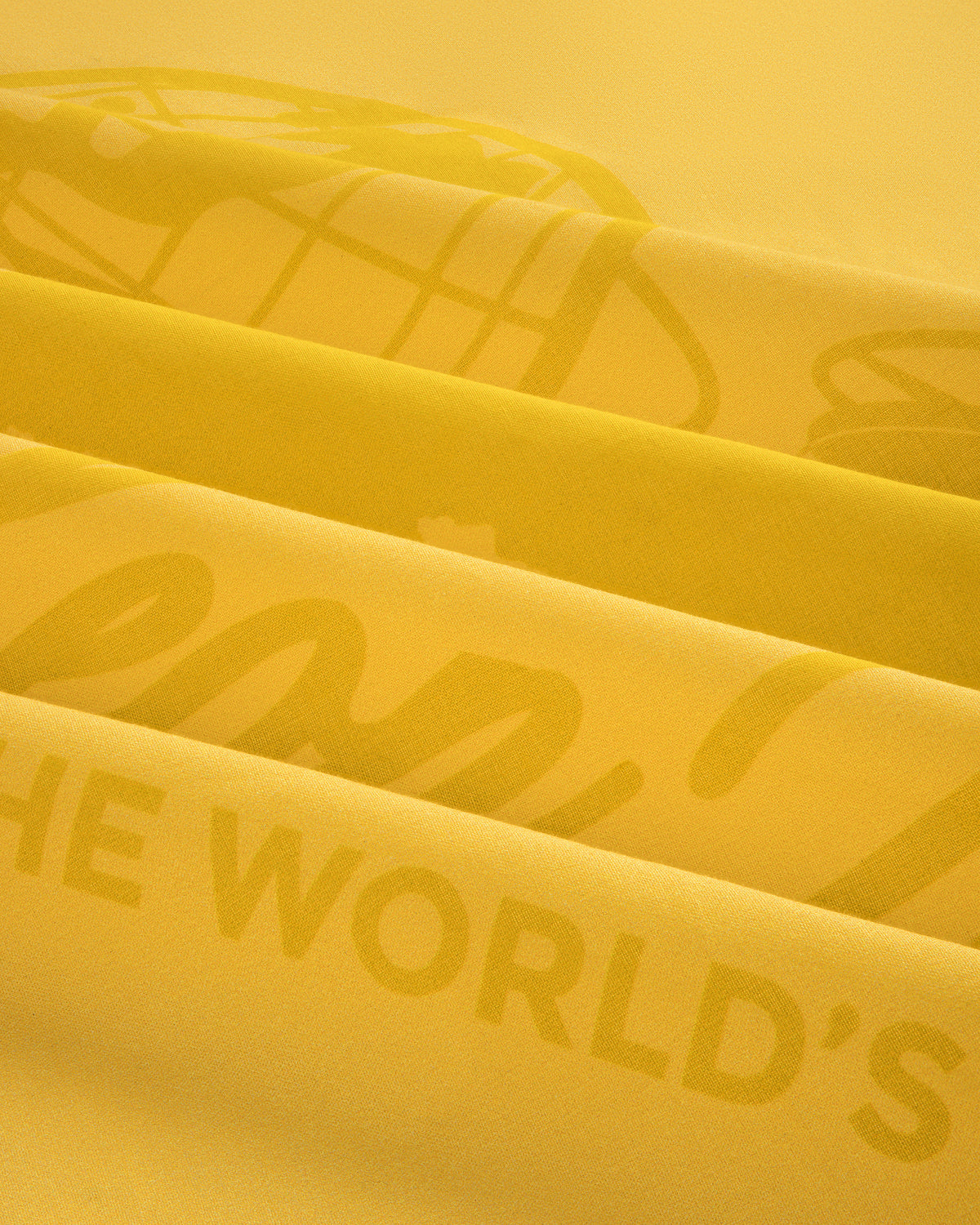 Close-up of folded Sun Faded Unisphere Bandana with faint printed text, including the words THE WORLDS.