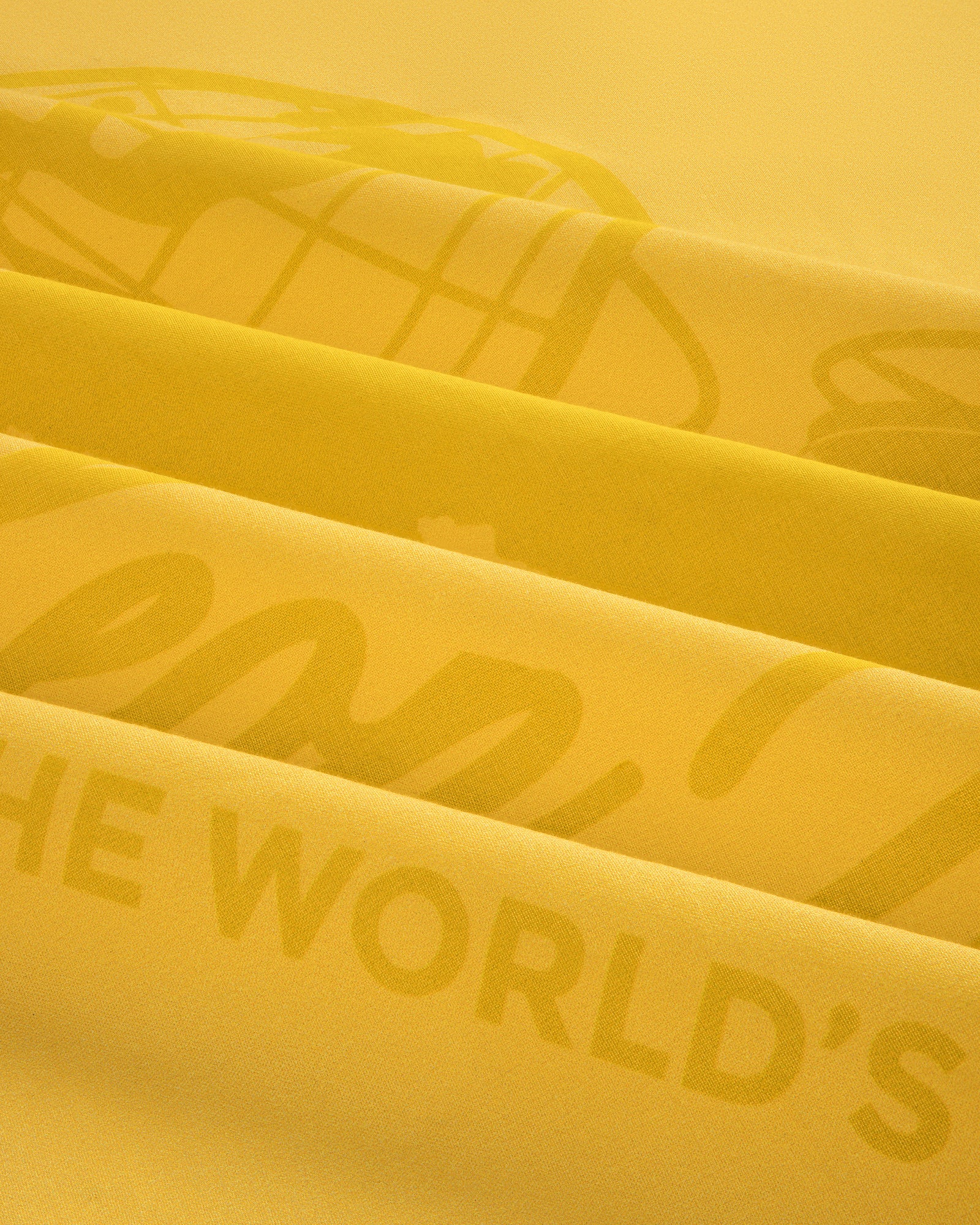 Close-up of folded Sun Faded Unisphere Bandana with faint printed text, including the words THE WORLDS.